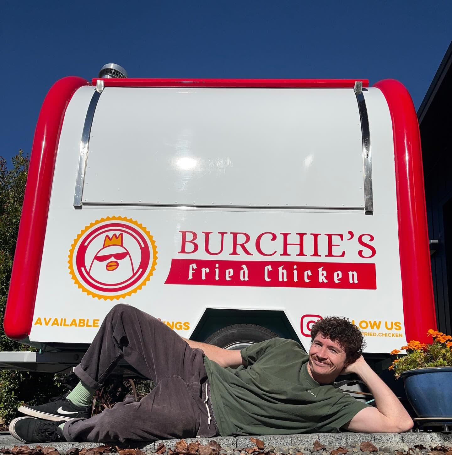 Thomas lying on the ground in front of the newly-wrapped Burchie's truck