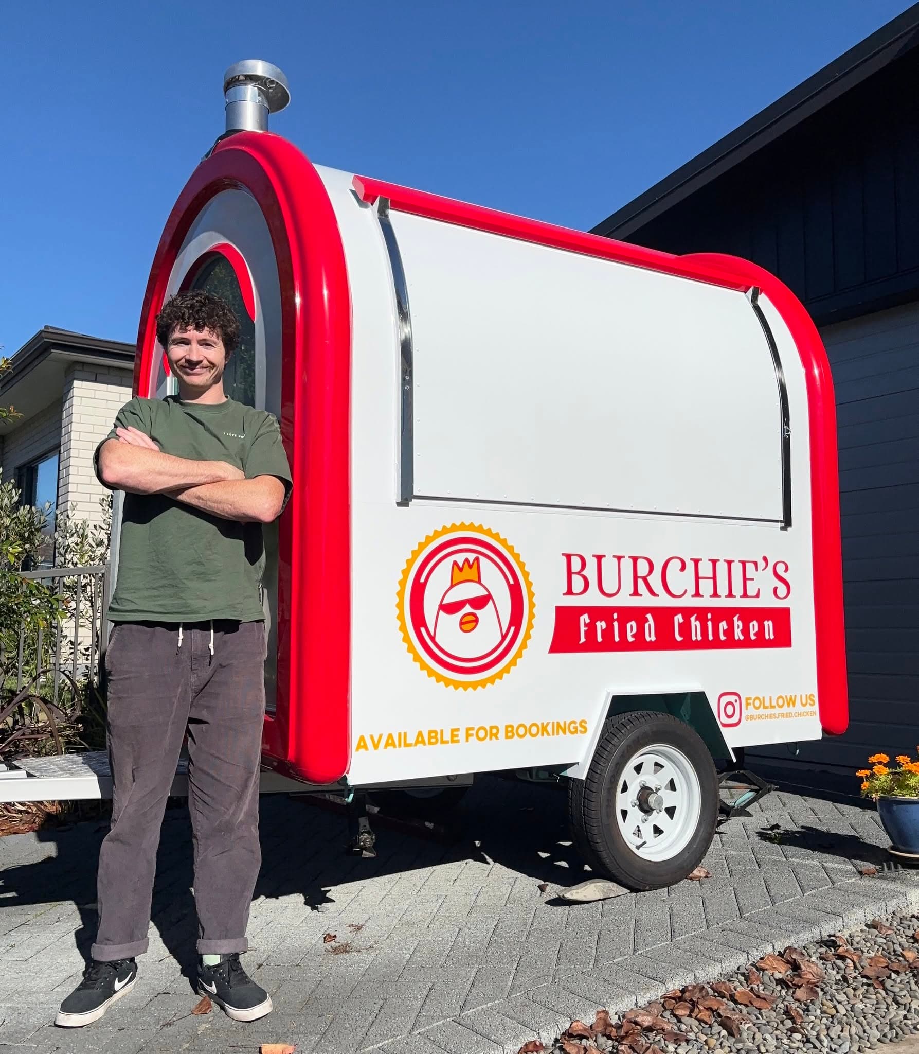 Thomas standing beside the red-and-white Burchie's Fried Chicken trailer