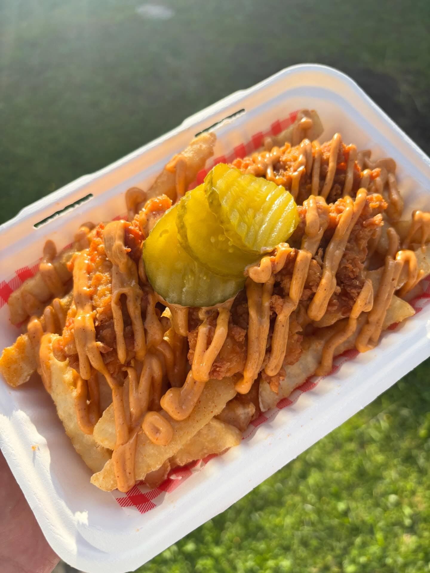 Loaded fries topped with fried chicken, sauce, and pickles